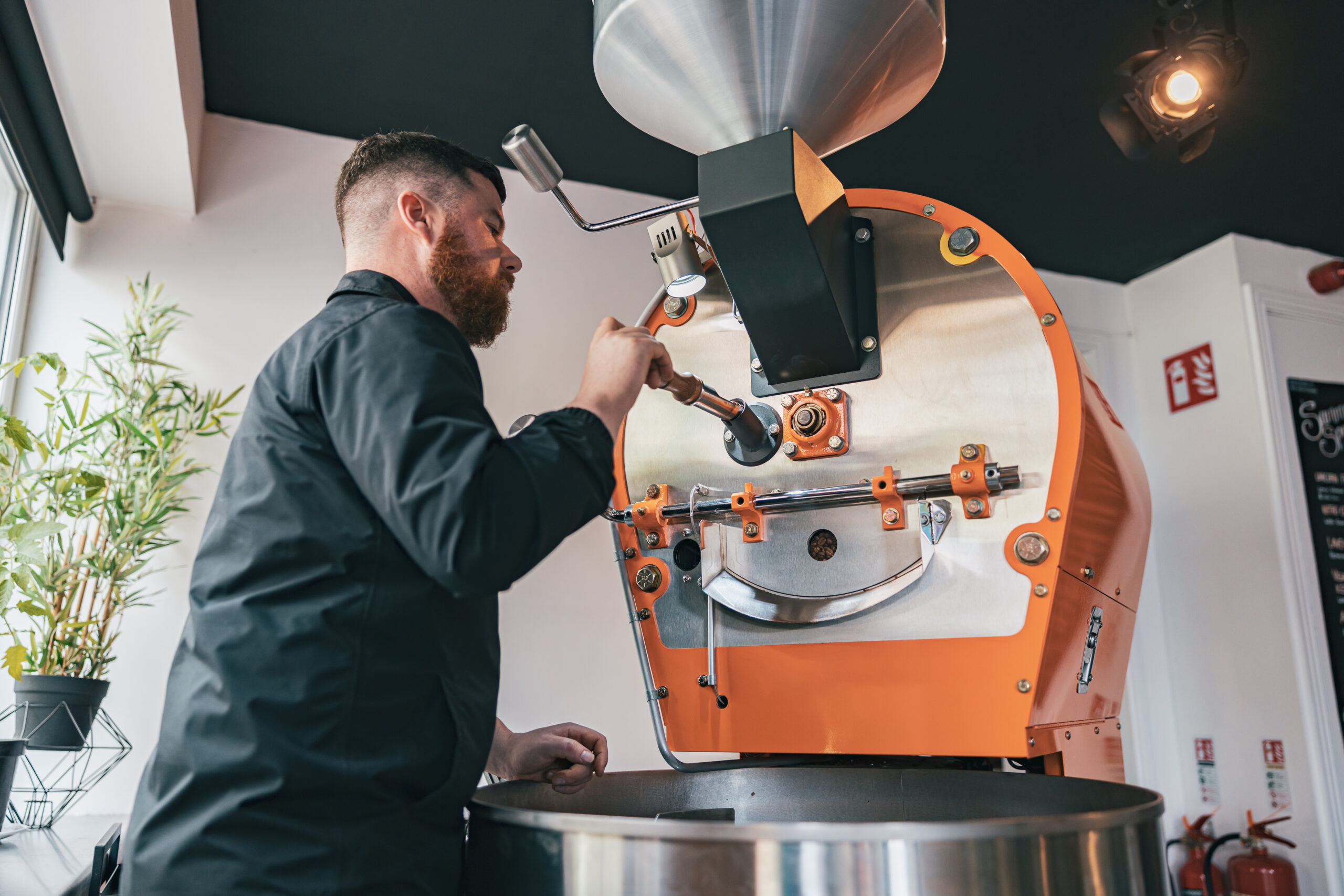 Professional Barista Operating Modern Coffee Bean Roasting Machine